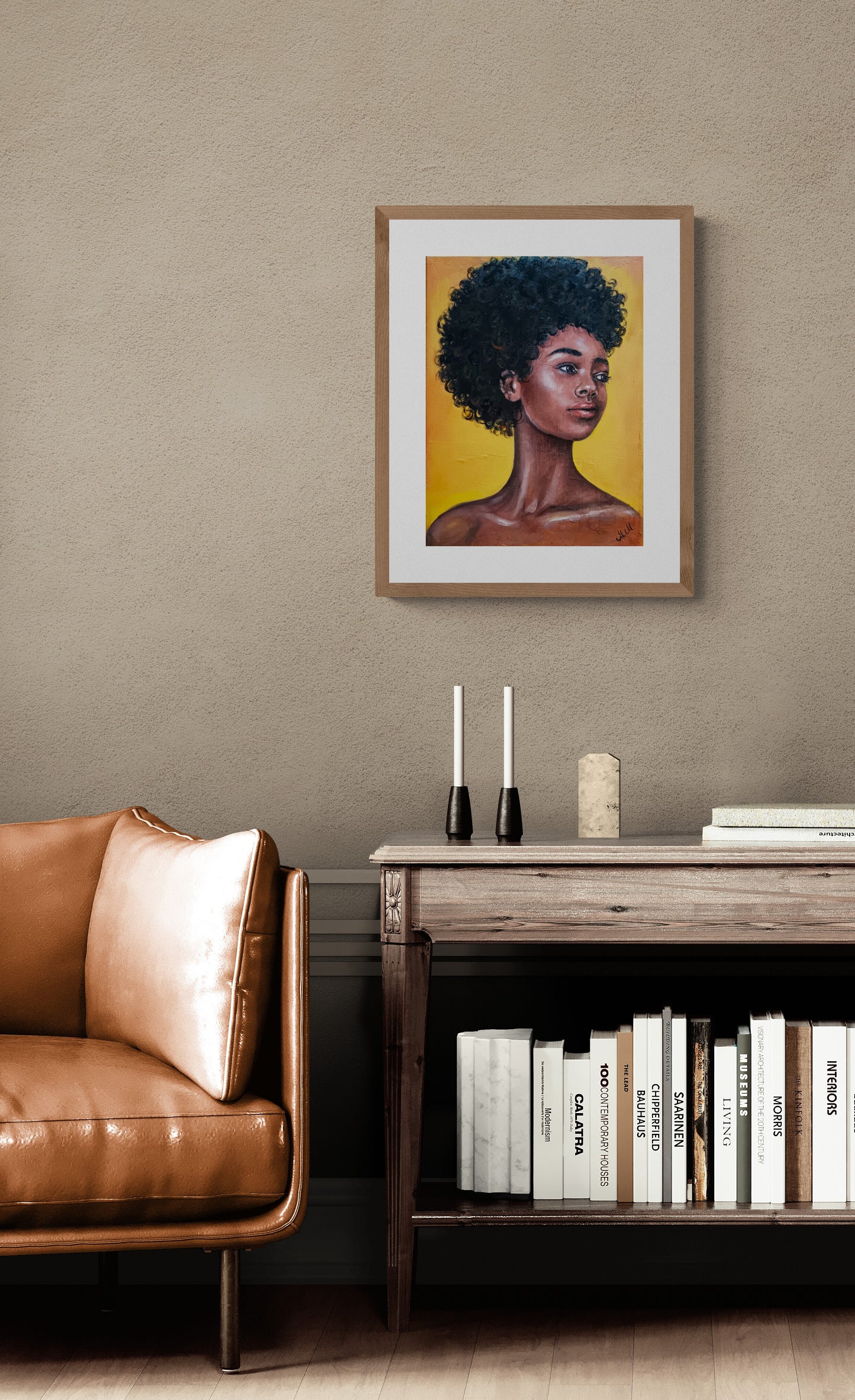 Framed artwork of a woman with an afro on a wall above a brown leather sofa and wooden side table.