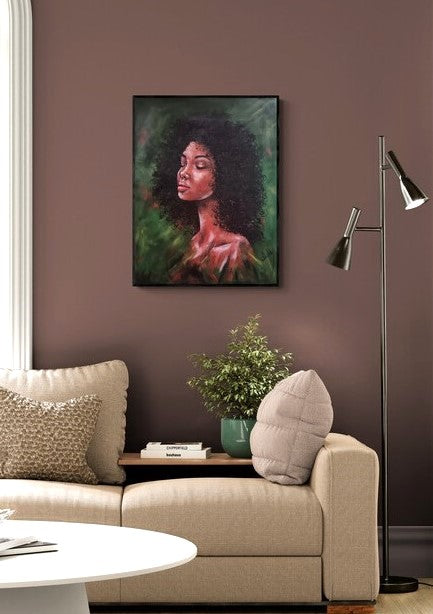 A framed portrait painting of a woman with dark curly hair and warm skin tones, displayed on a mauve wall above a beige sofa in a styled living room setting.