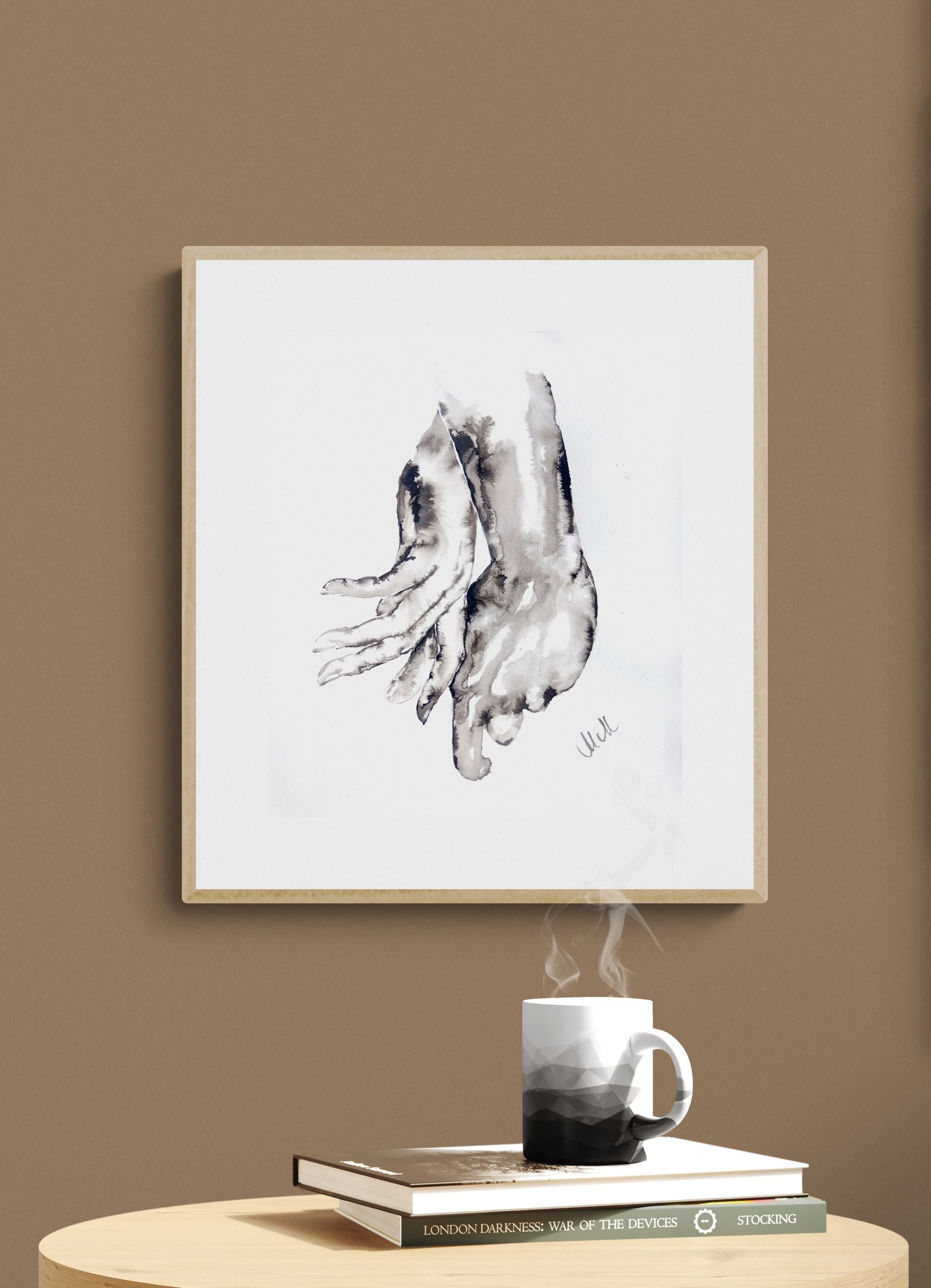 Framed black and white abstract art print on a wall with a steaming mug and books on a table below.