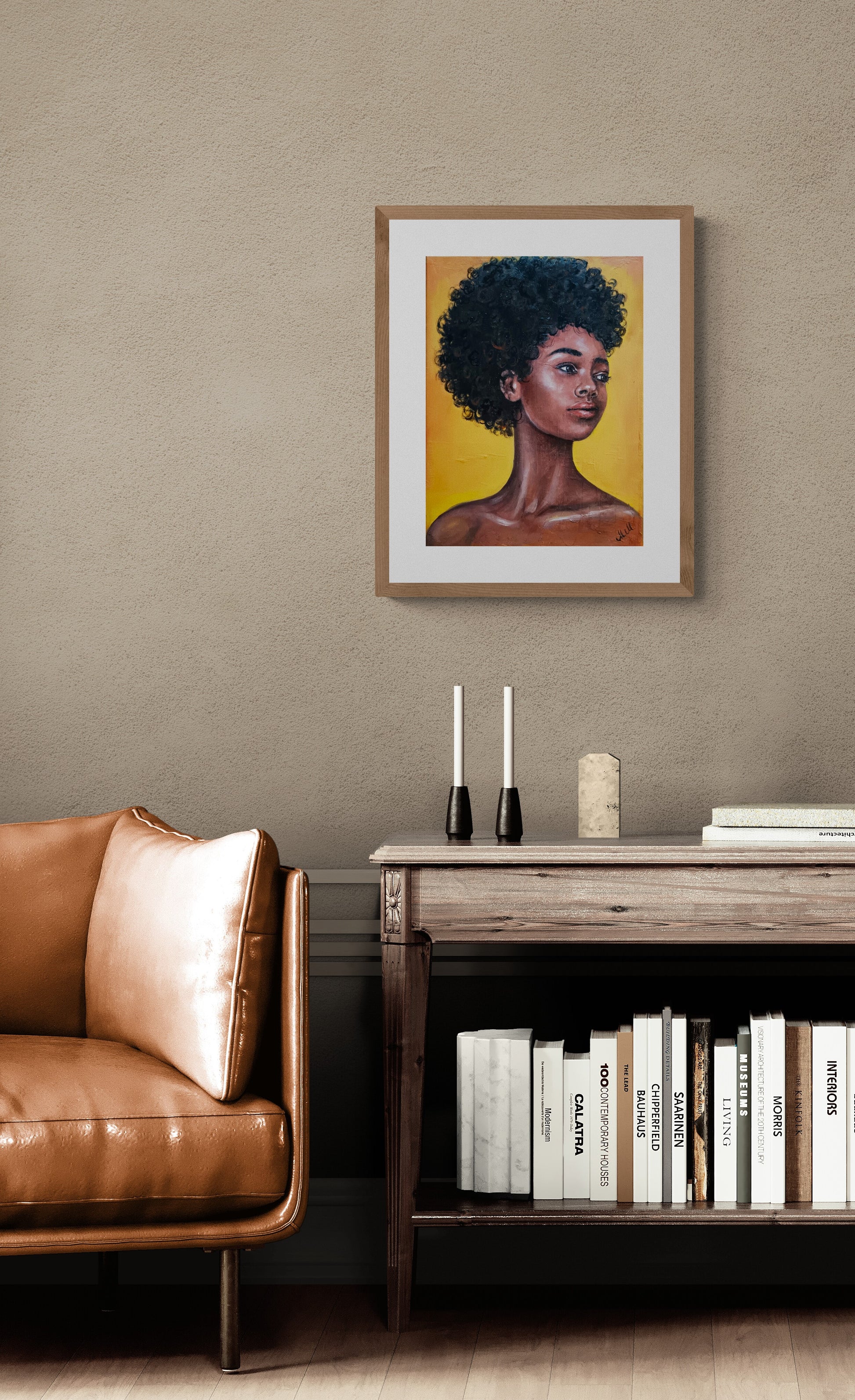 Framed artwork of a woman with an afro on a wall above a brown leather sofa and wooden side table.