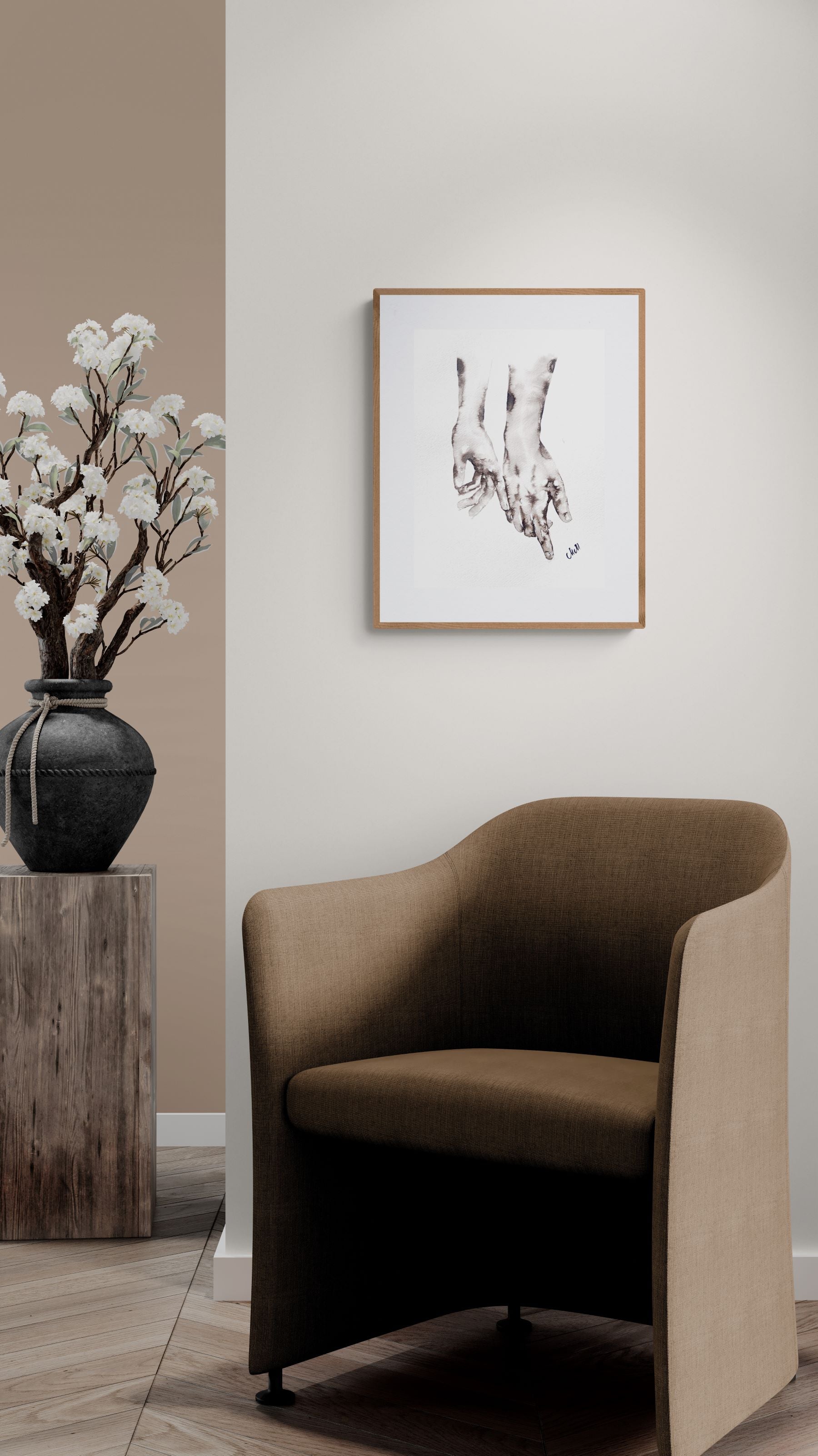 Modern brown chair in a room with a vase of flowers and framed artwork on the wall.