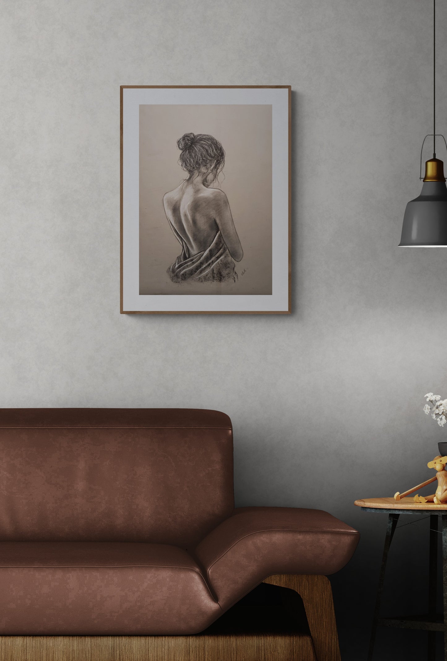 Framed artwork of a woman on a wall above a brown sofa in a room.