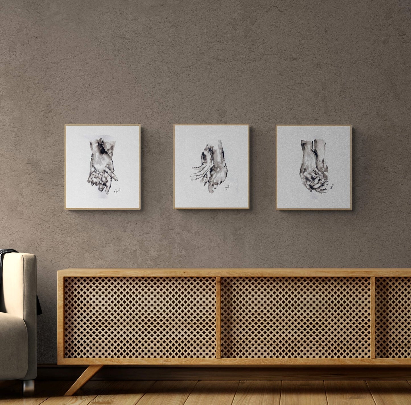 Three framed black and white artworks on a textured wall above a wooden sideboard.