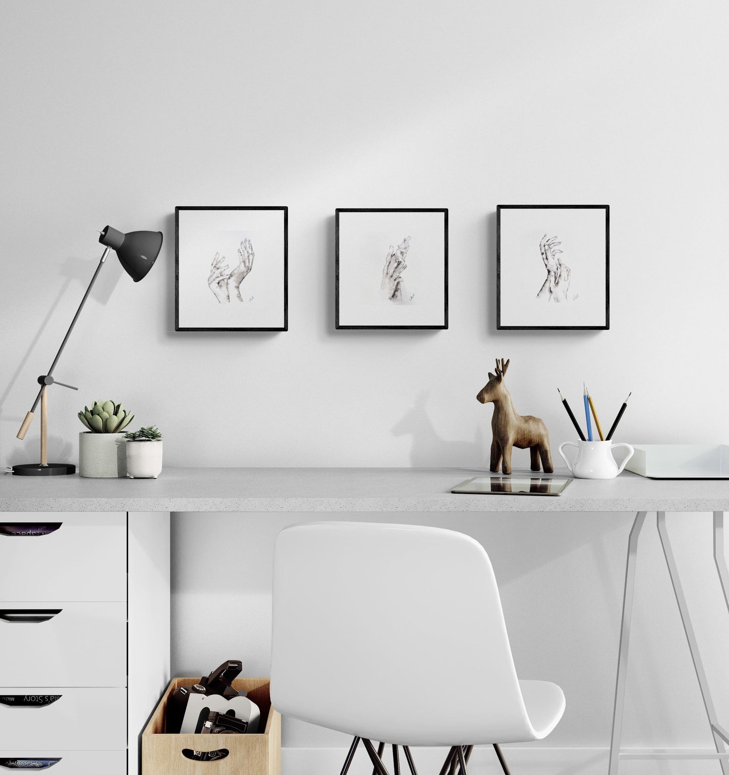 Modern office desk with white chair, lamp, and framed artwork on a light gray wall.