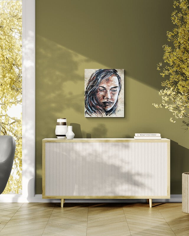 A square canvas art print featuring a stylized portrait of a woman, displayed on an olive green wall above a white ribbed sideboard in a modern room setting.
