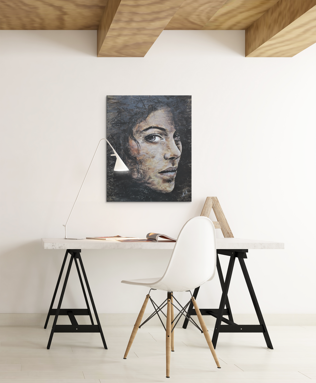 A  portrait painting of a woman hangs on a white wall above a minimalist desk setup with a white chair, lamp, and wooden table in a bright room.