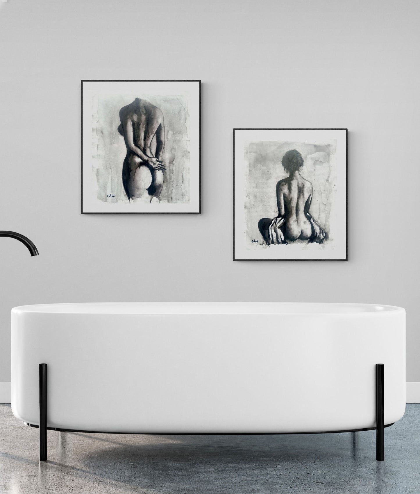 Modern white freestanding bathtub with framed black and white artworks on a gray wall.