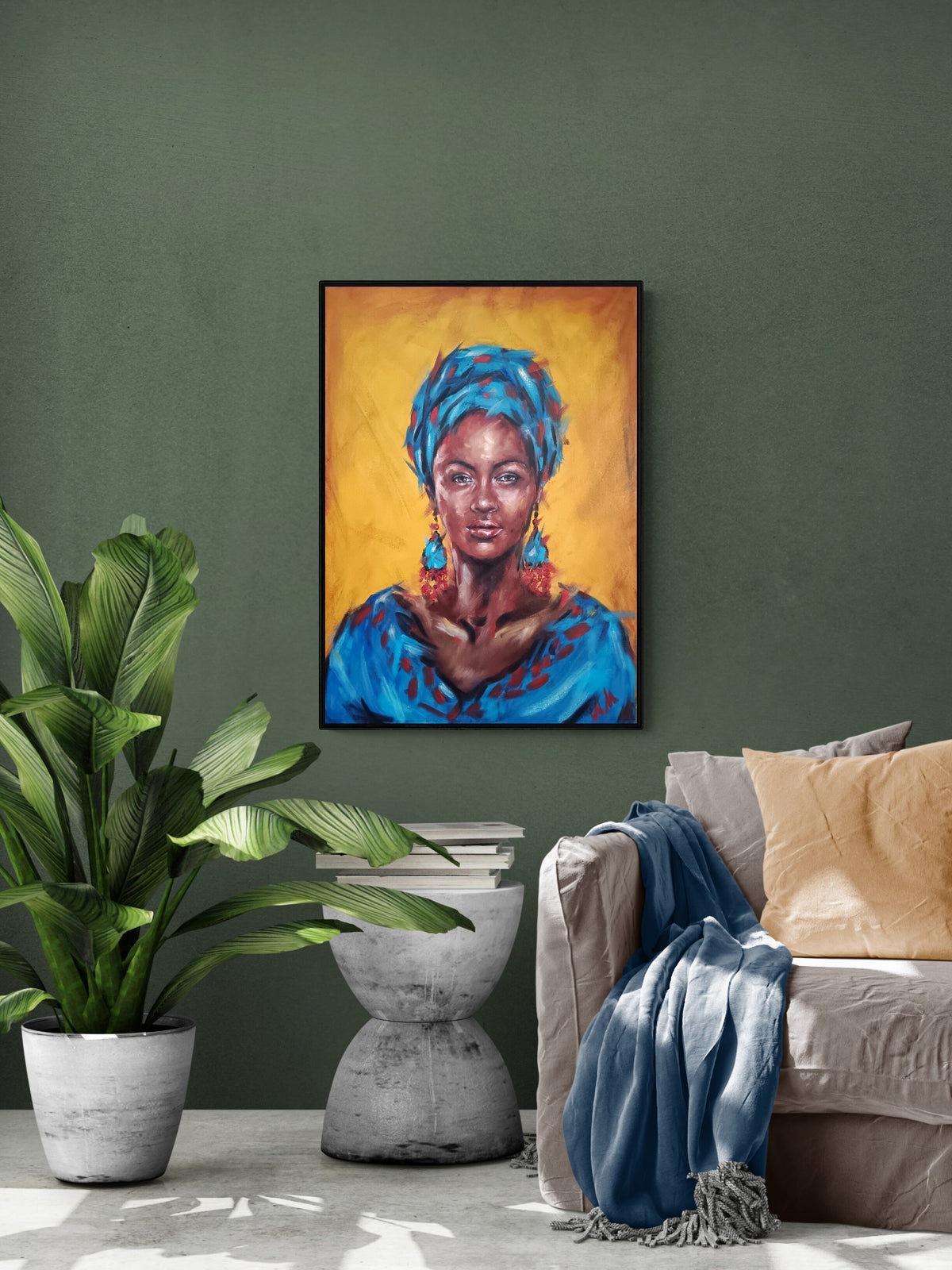 A framed vertical portrait painting of a woman in a bright blue headwrap and blue garment against a warm yellow-orange background, displayed on a dark green wall above a sofa with a blue throw and a potted plant nearby.